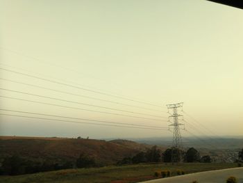 Electricity pylon on field against clear sky