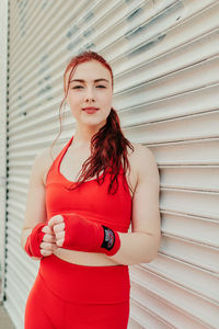 Portrait of woman standing against red wall