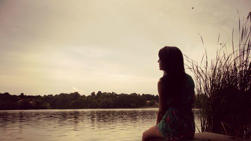Rear view of woman looking at lake against sky