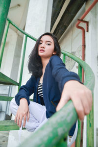 Portrait of young woman sitting on railing