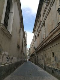 Empty road amidst buildings against sky