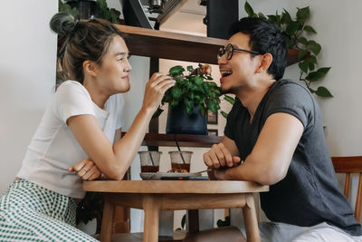 Side view of friends using laptop while sitting at home