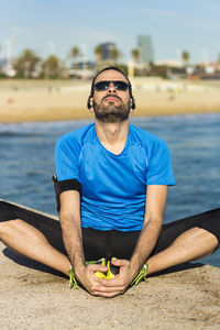 Man exercising on sand against sea at beach