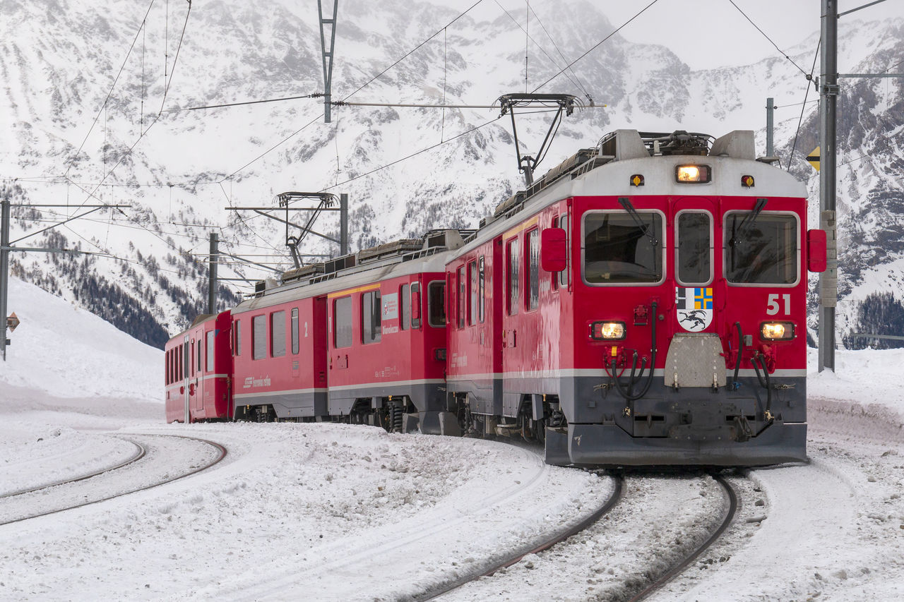 TRAIN ON RAILROAD TRACK BY SNOWCAPPED MOUNTAIN