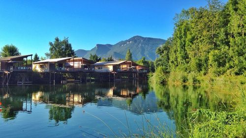 Scenic view of lake and mountains against clear blue sky