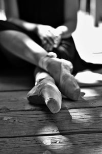 Low section of ballet dancer sitting on hardwood floor