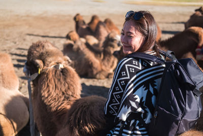 Smiling woman sitting on camel in desert