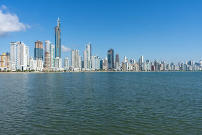 Sea by buildings against sky in city