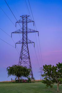 Low angle view of electricity pylon on field against sky