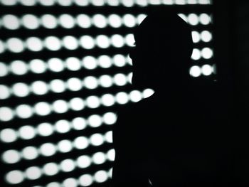 Close-up of silhouette person standing against illuminated window