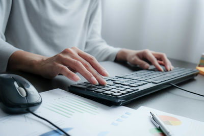 Midsection of businesswoman using laptop on table at office