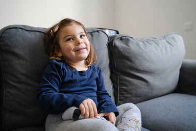 Smiling girl sitting on sofa at home