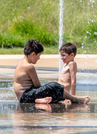 Two brothers cool off in a fountain at a local splash pad, on a hot summer's day