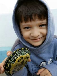 Portrait of cute smiling boy holding tortoise