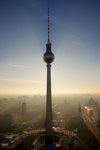 Communications tower in city against sky