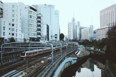 Railroad tracks amidst buildings in city against sky