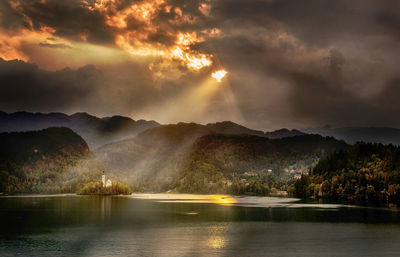 Scenic view of lake against dramatic sky during sunset