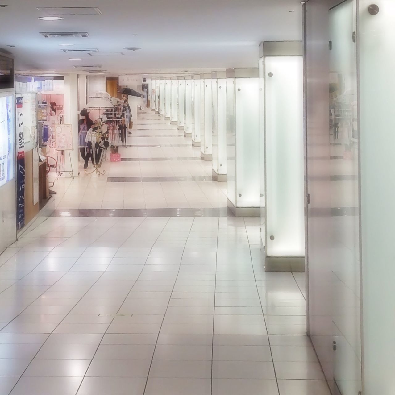indoors, corridor, empty, ceiling, the way forward, flooring, tiled floor, architecture, absence, built structure, illuminated, modern, tile, subway, diminishing perspective, door, interior, in a row, reflection, wall - building feature