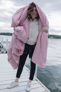 Full length of beautiful woman standing on jetty against lake