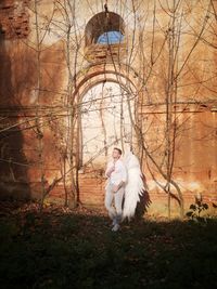 Full length of couple sitting on bare tree