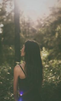 Woman standing by tree in forest