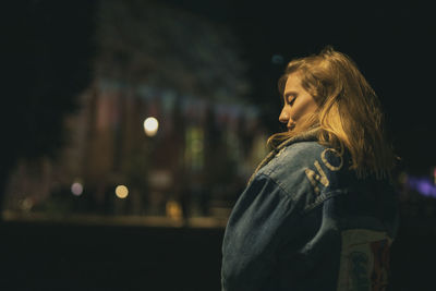 Fashionable young woman in city at night