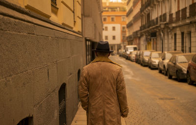 Rear view of man in hat and coat on street during sand storm day. madrid, spain