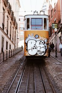 Graffiti on railroad tracks in city against sky
