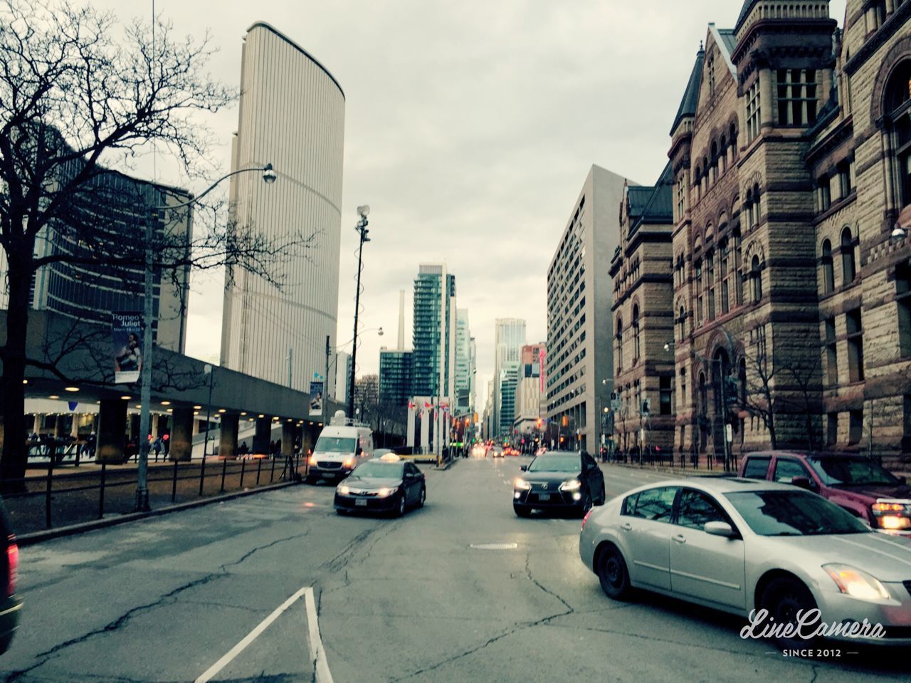 CARS ON CITY STREET BY BUILDINGS AGAINST SKY