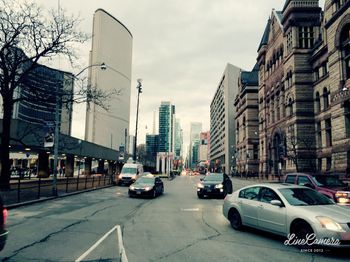 Cars on city street against sky