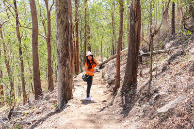 Full length of woman standing amidst trees in forest