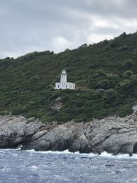 Scenic view of sea by mountain against sky