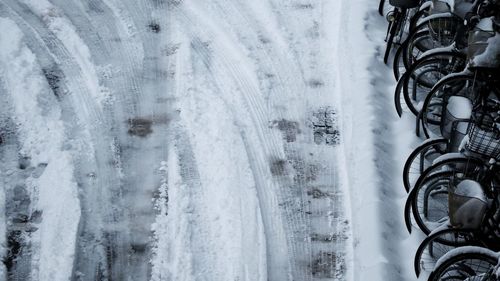 High angle view of bicycles by tire tracks on snow covered road