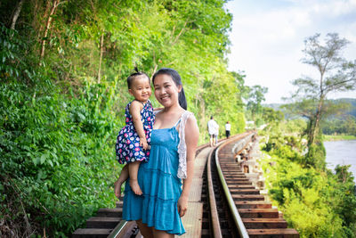 Portrait of a smiling woman standing on railroad track