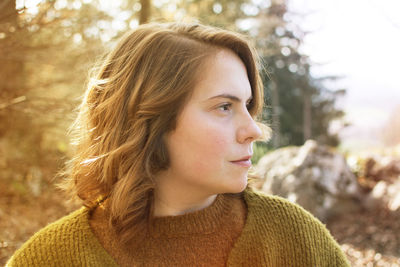 Close-up of thoughtful woman looking away against trees in forest