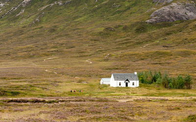 House on field against mountain