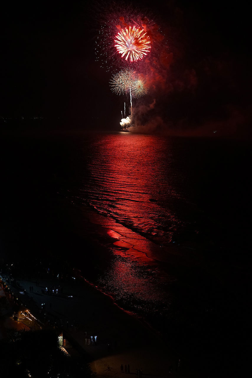 LOW ANGLE VIEW OF FIREWORK DISPLAY OVER SEA AGAINST SKY