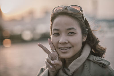 Close-up portrait of smiling mid adult woman showing peace sign