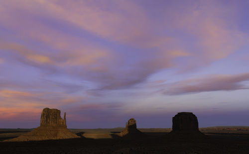 Rock formations on landscape against sunset sky