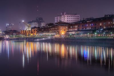 Illuminated buildings reflecting on river at night