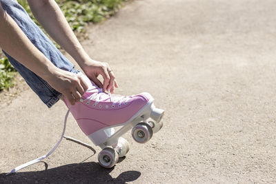 Legs of a woman tying pink roller skates