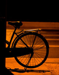 Silhouette bicycle by street during sunset