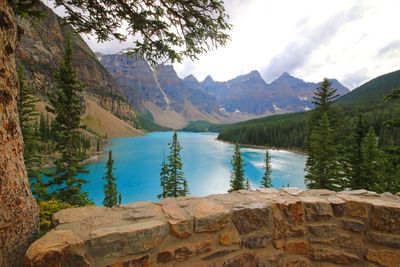 Scenic view of moraine lake by mountains against cloudy sky
