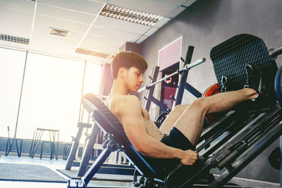 Shirtless young man exercising gym