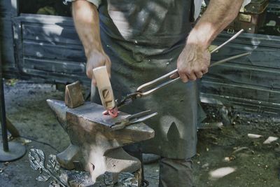 Midsection of blacksmith working with metal