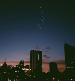 Low angle view of illuminated cityscape against sky at night