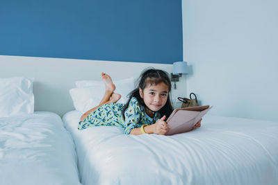 Little girl playing ipad table on bed