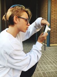 Side view portrait of a serious young man holding eyeglasses