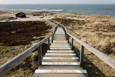 Boardwalk leading towards sea against sky