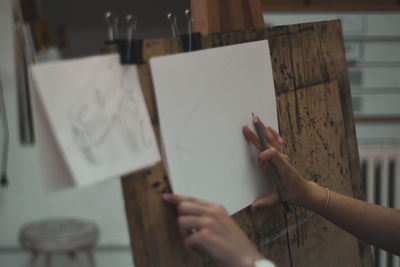 Cropped image of woman holding paper on canvas